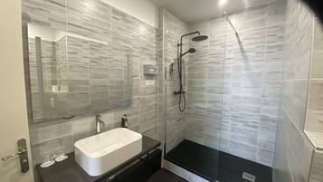 A modern bathroom with a glass-enclosed shower, a white sink, and a black vanity.