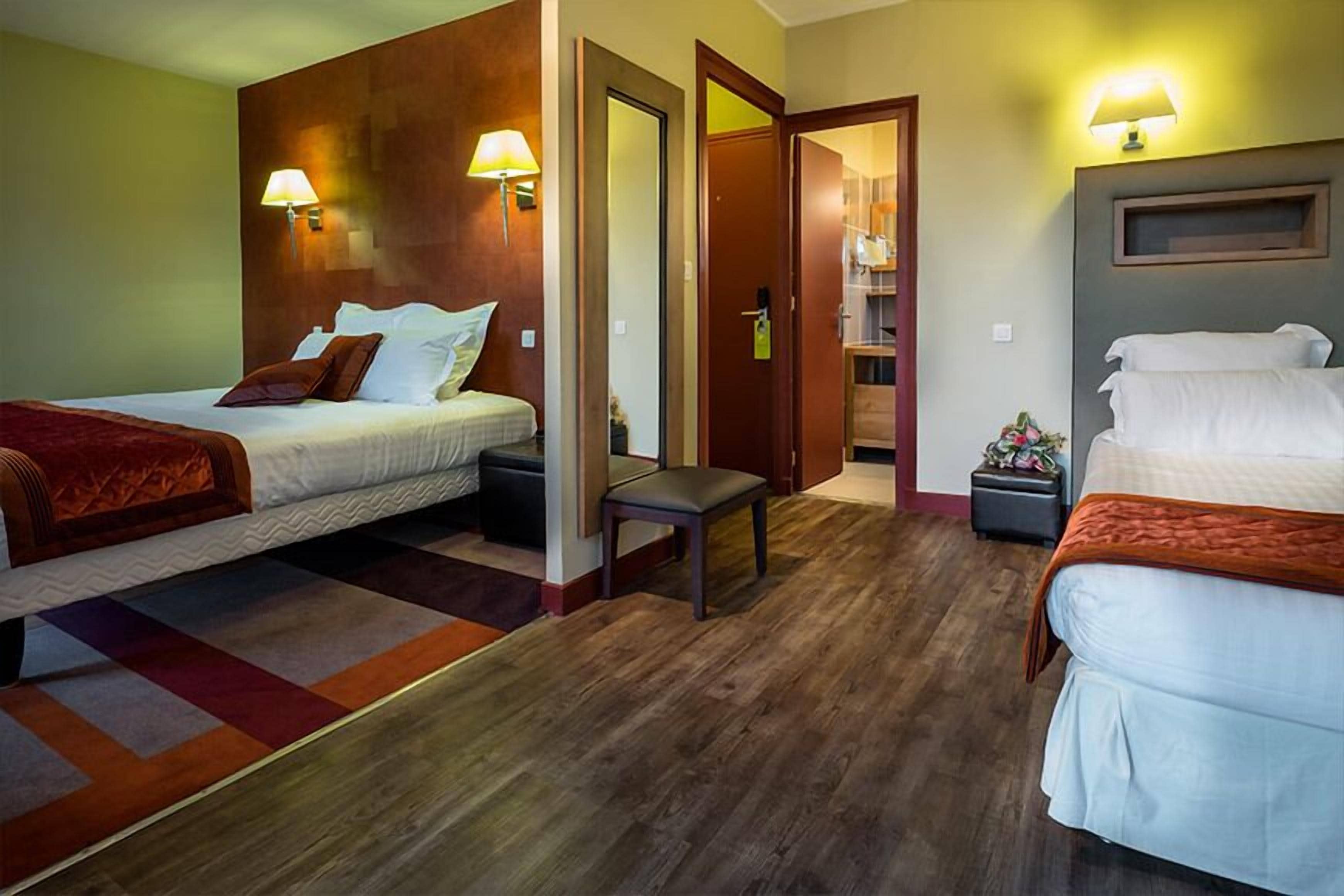 Habitación de hotel con dos camas, un banco, un armario y una mesita.