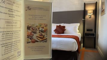 A hotel room with a bed, a nightstand, and a wall-mounted lamp.