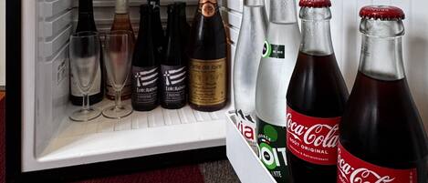 Un refrigerador abierto con diversas bebidas, incluyendo vino, champán y Coca-Cola.