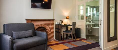 A living room with a sofa, a fireplace, a desk, and a television.