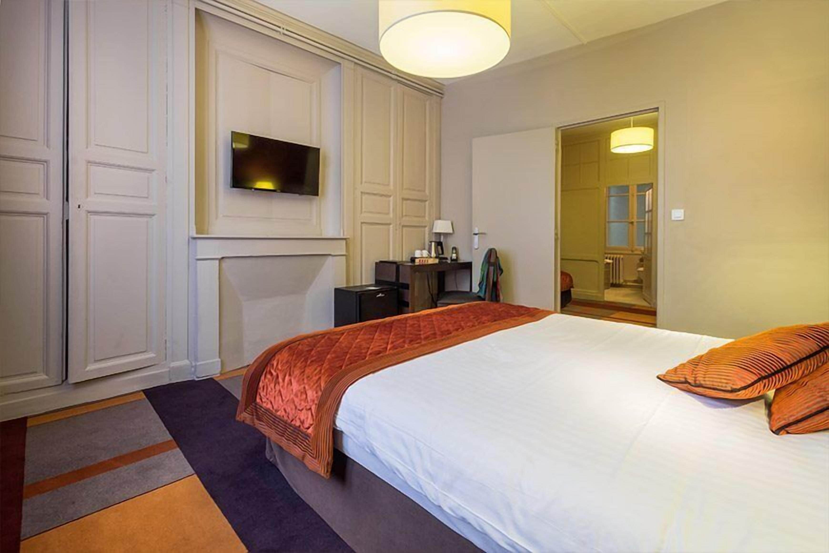 A hotel room with a bed, a television, a desk, and a mirror.