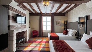 A hotel room with a fireplace, a television, a bed, a bedside table, and a window with curtains. - Hôtel Bellevue (Amboise)