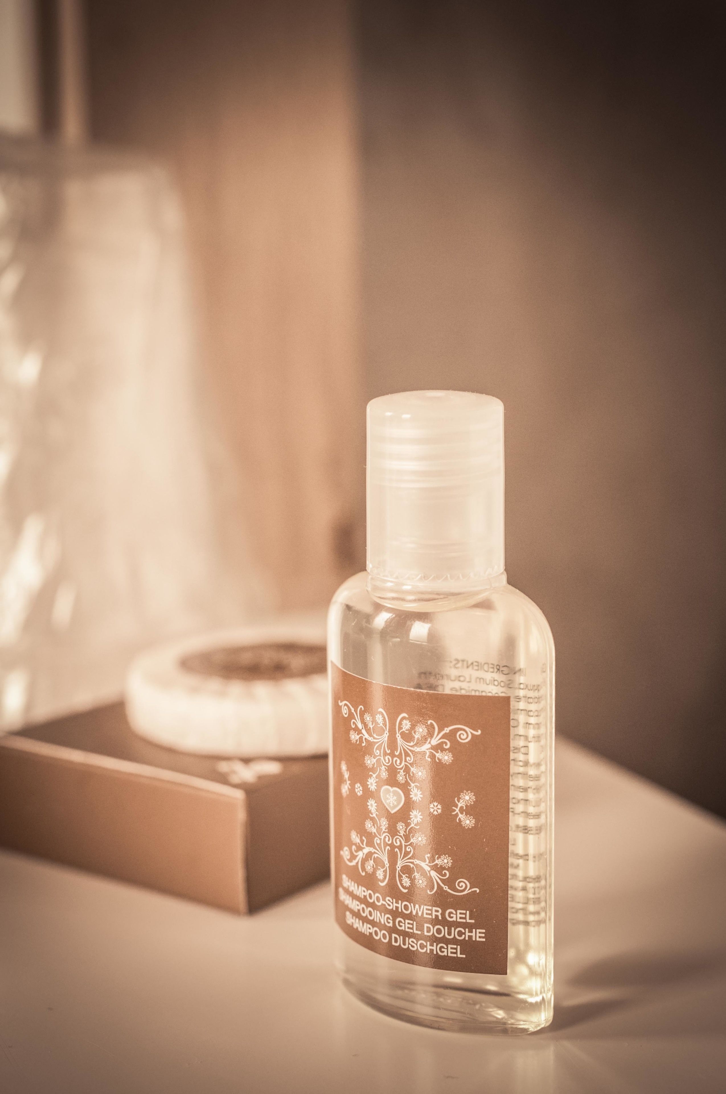A clear bottle of shower gel with a label, placed on a surface with a blurred background.