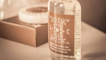 A clear bottle of shower gel with a label, placed on a surface with a blurred background.