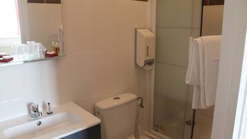 Un baño con lavamanos, inodoro y cabina de ducha de vidrio.
