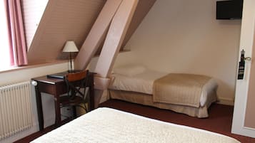 Ein Schlafzimmer mit einem Bett, einem Schreibtisch, einem Sessel, einer Heizung und einem an der Wand befestigten Fernseher.