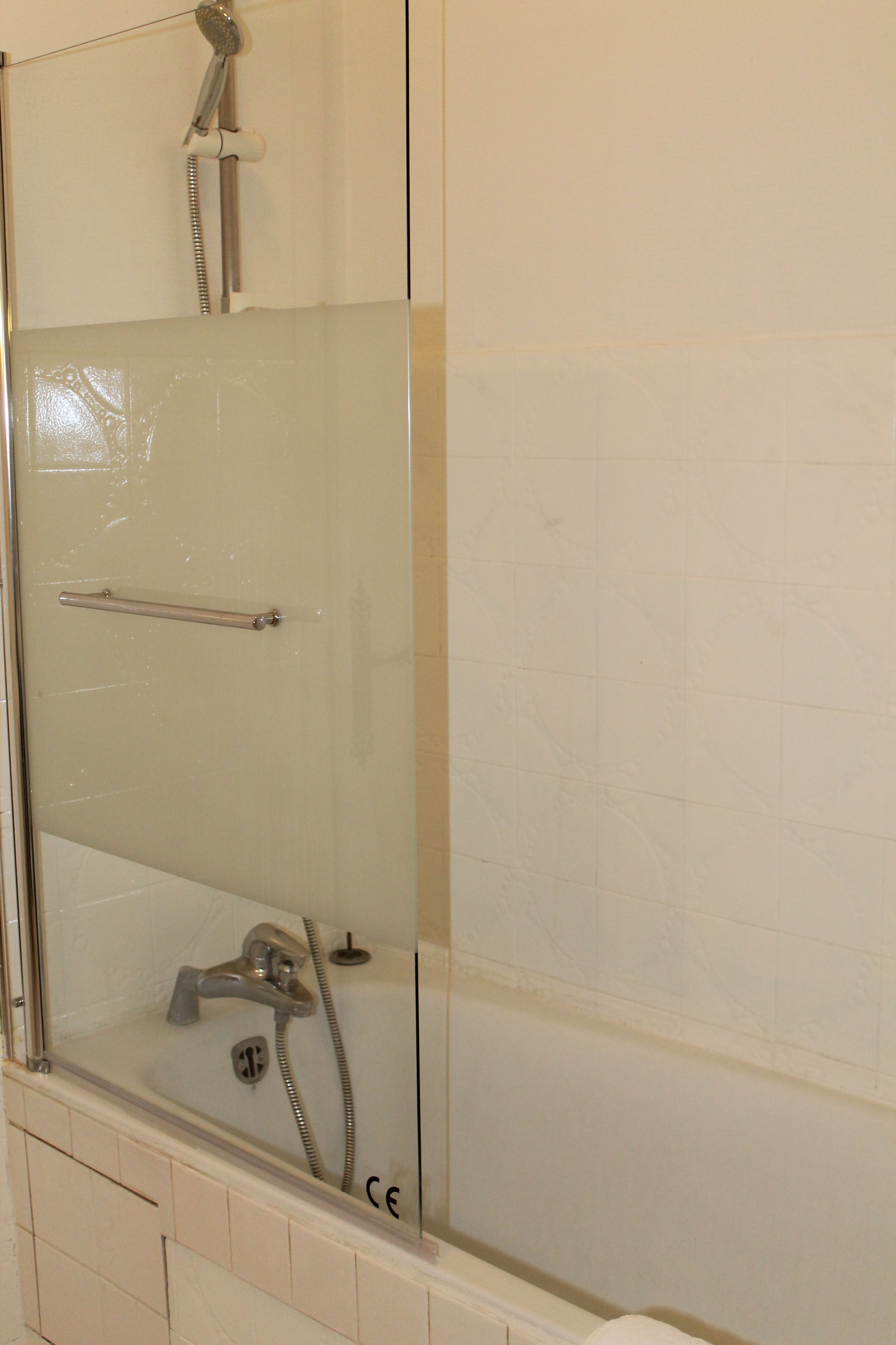 Un espace douche clos par des parois de verre, équipé d’un pommeau de douche à main et d’un robinet à main.