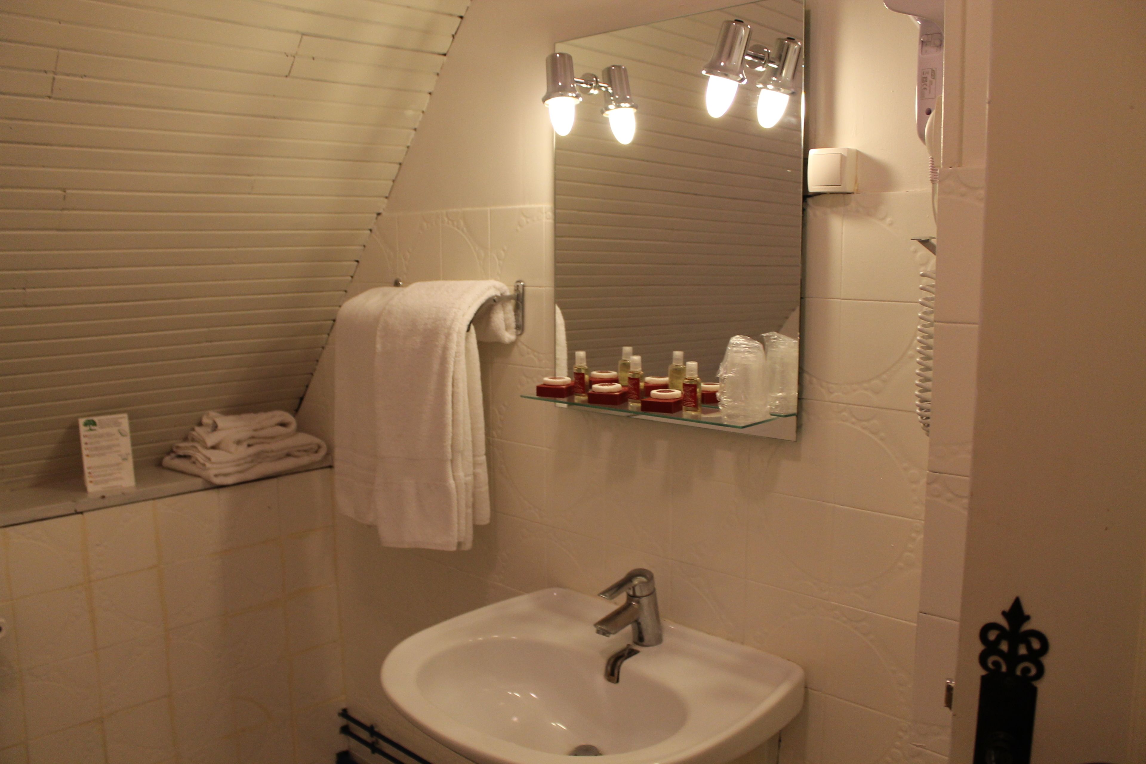 Une salle de bain avec un lavabo blanc, un miroir et un porte-serviettes.