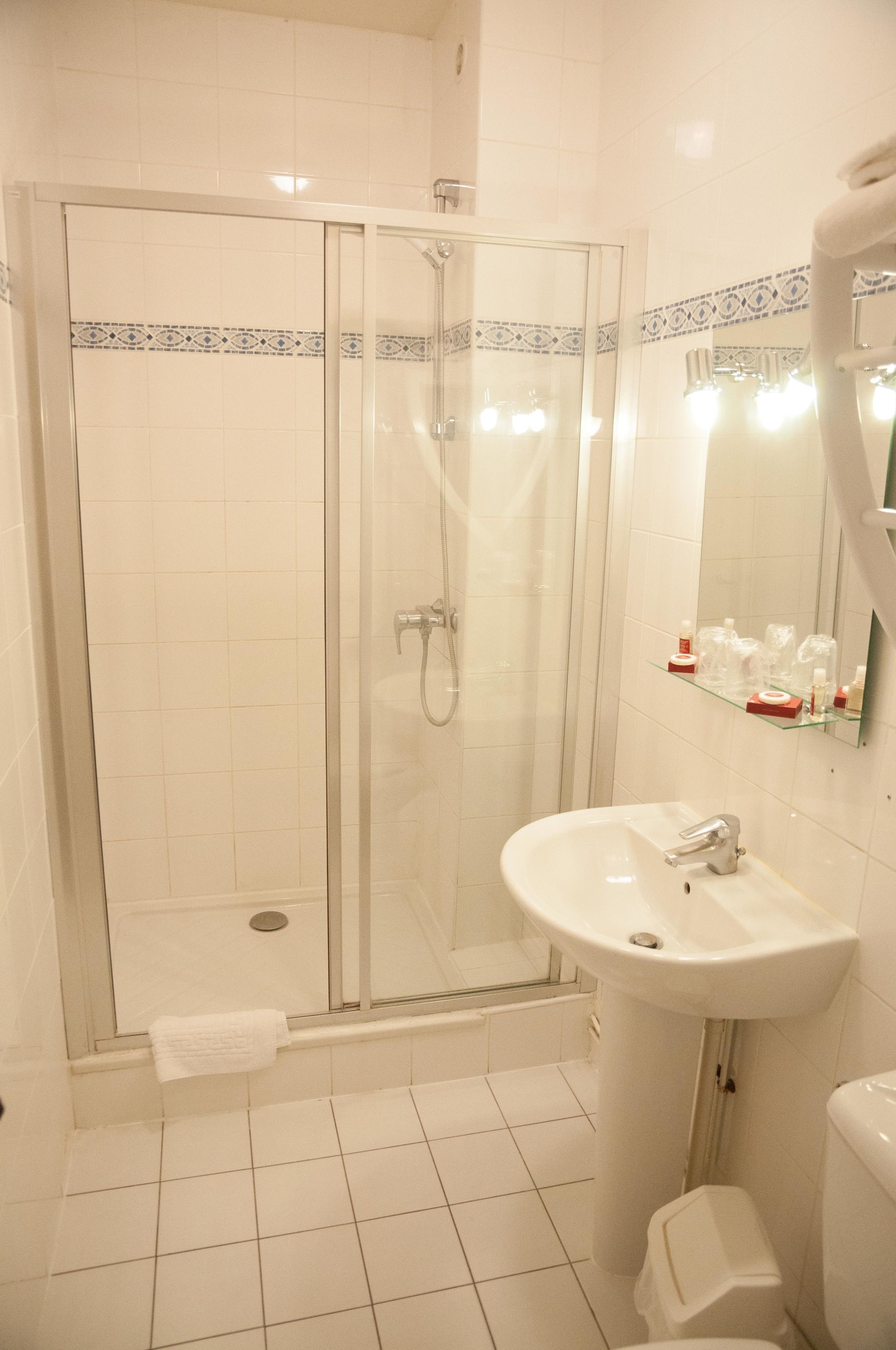A bathroom with a glass-enclosed shower, a white sink, and a mirror above it.