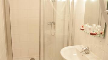 A bathroom with a glass-enclosed shower, a white sink, and a mirror above it.