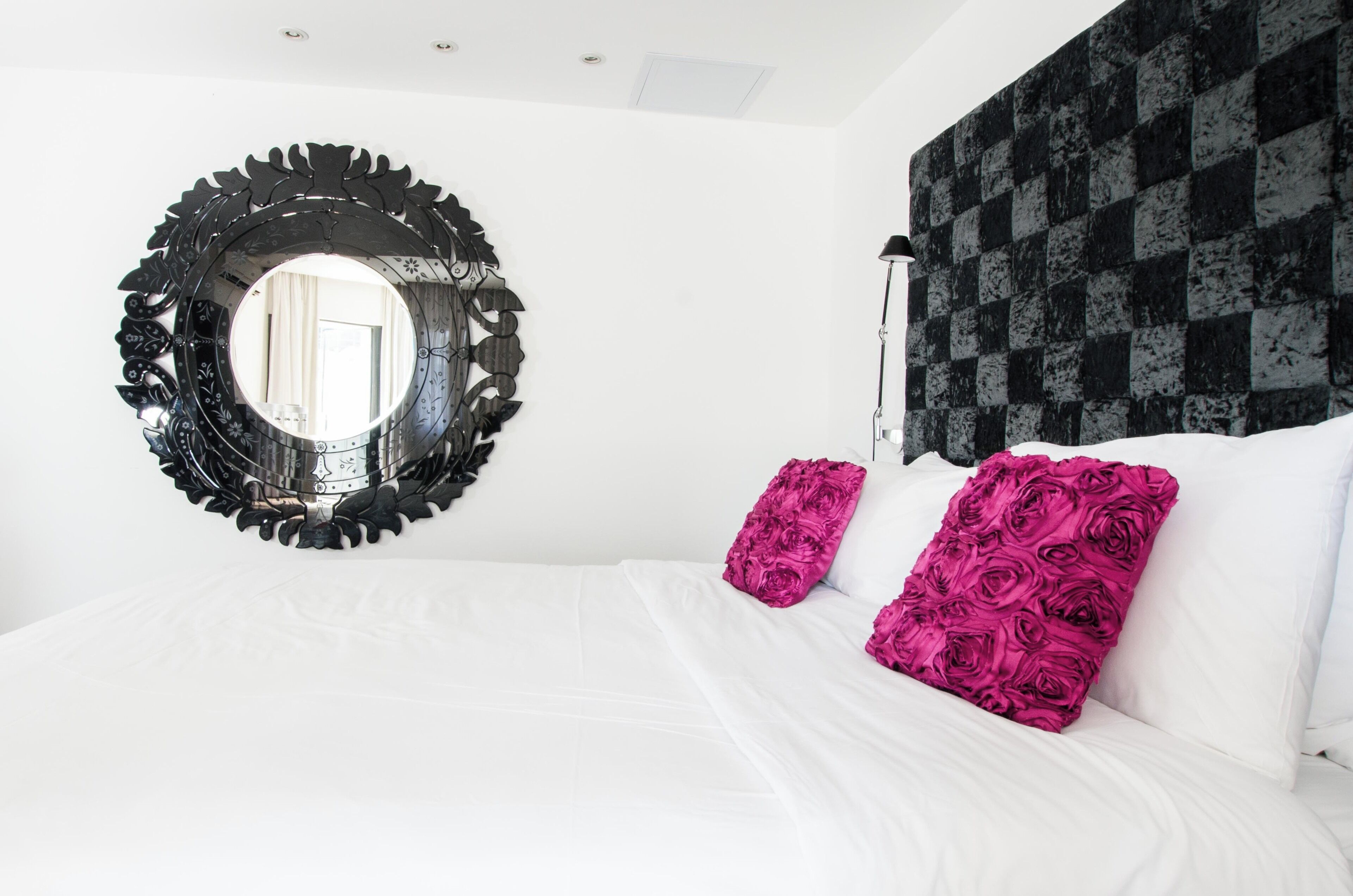 A bedroom with a large bed, a round mirror, and a patterned wall.