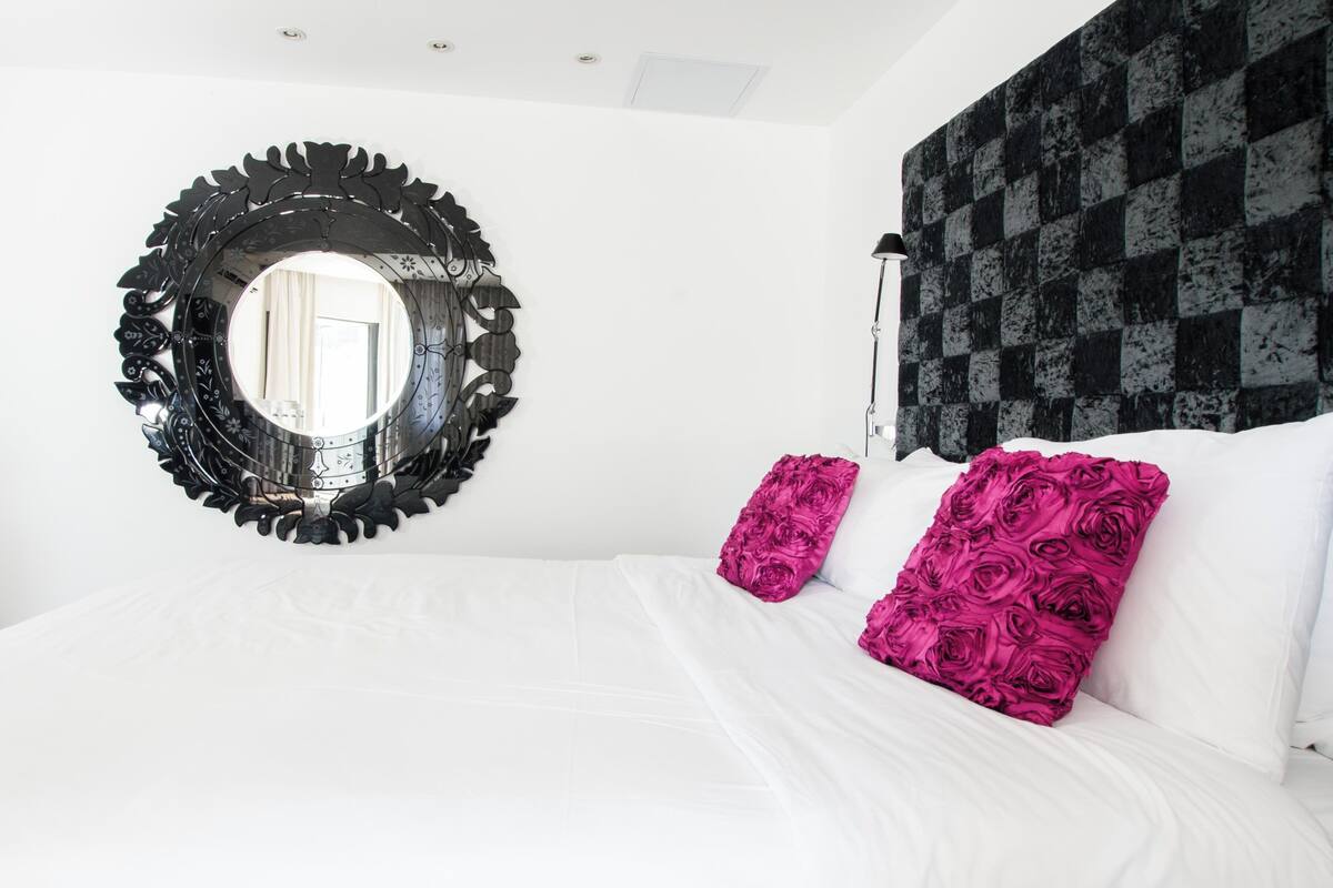 A bedroom with a large bed, a round mirror, and a patterned wall.
