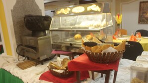 A buffet setup with various food items, a bread display, and a coffee machine. - Somatel Hotel (Douala)
