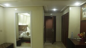 A hotel room with a bed, a desk, a chair, a wardrobe, and a bathroom visible through an open door. - Somatel Hotel (Douala)