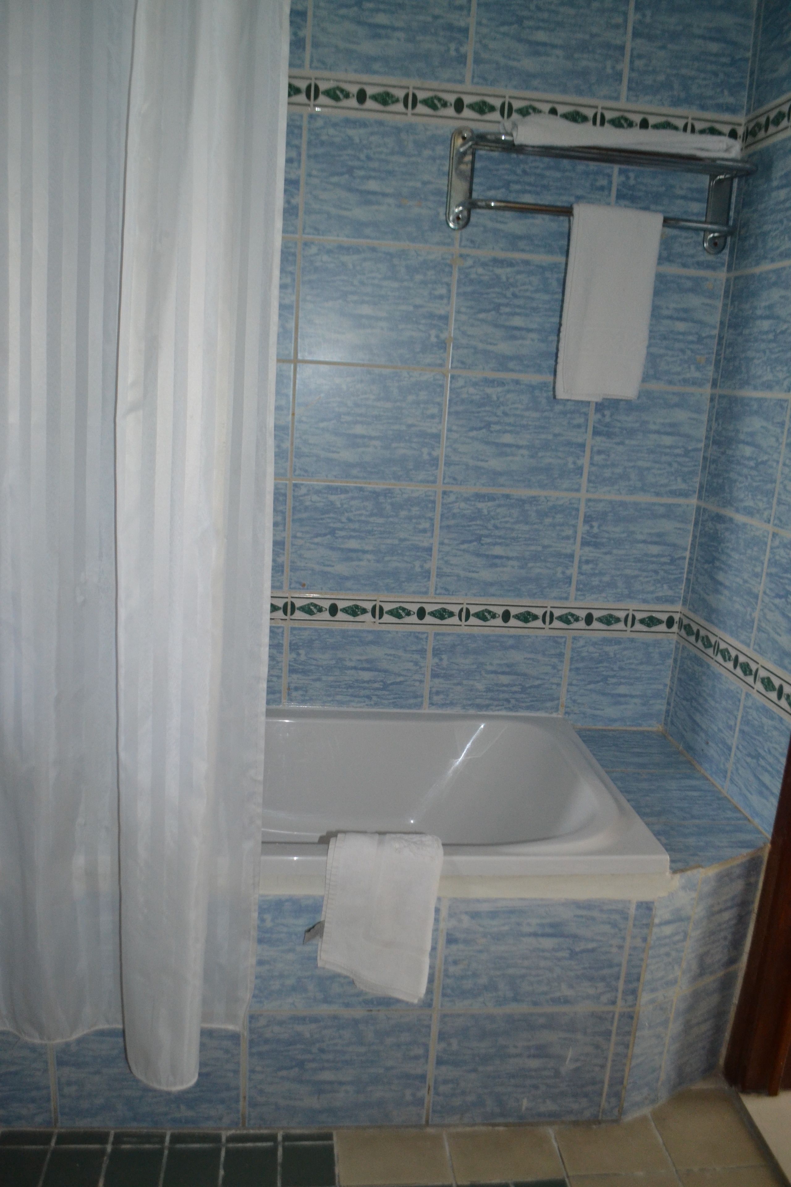 Une salle de bain avec une baignoire, un porte-serviettes et des murs recouverts de carreaux bleus.