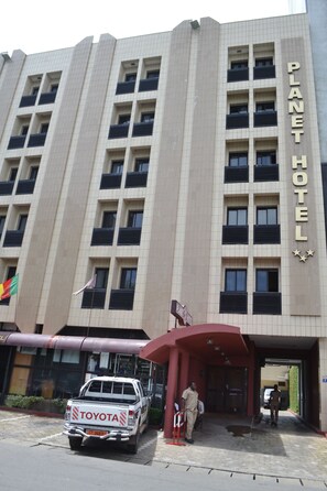 A building with a sign reading "PLANET HOTEL" and a white pickup truck parked in front. - Planet Hotel (Douala)