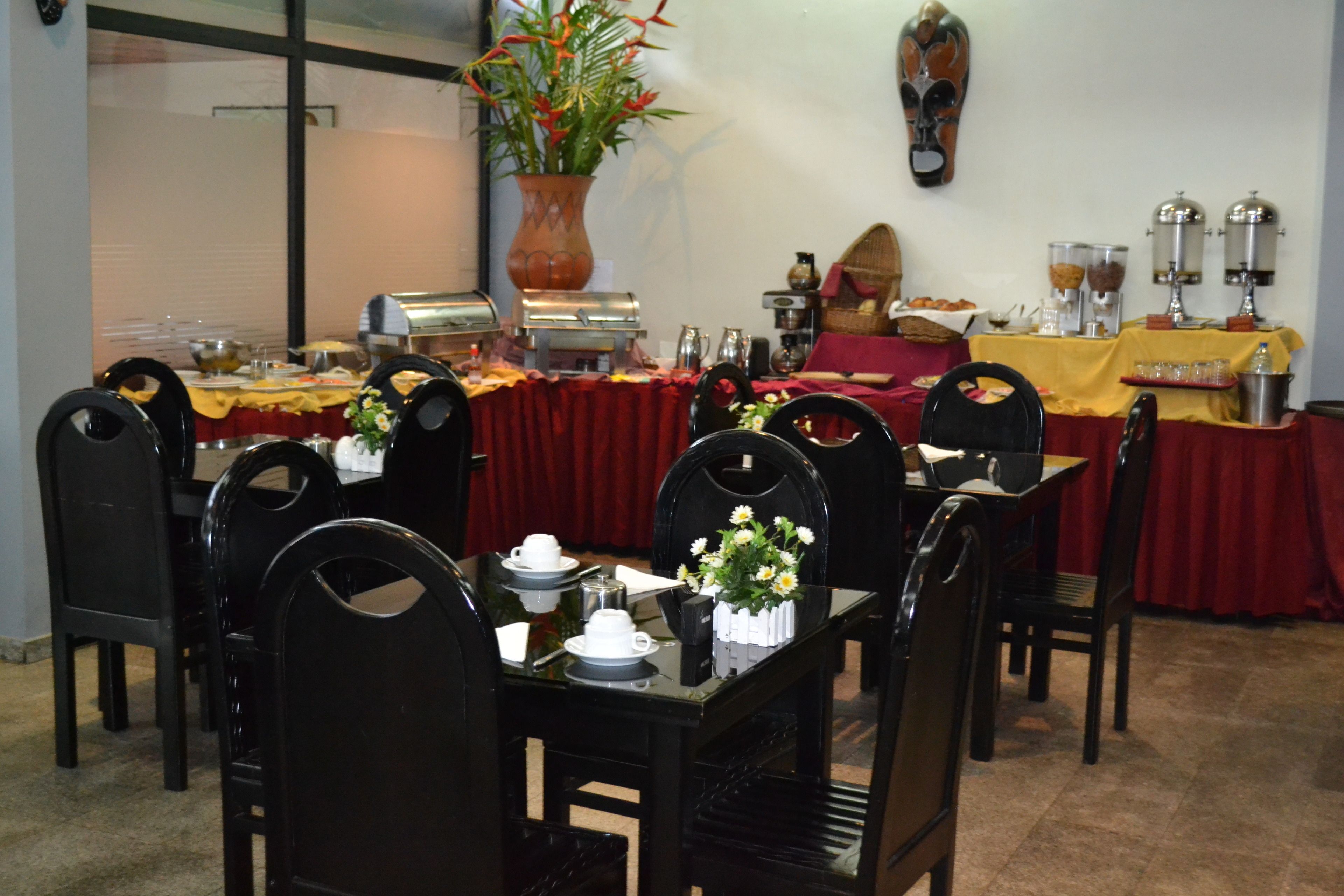 Un comedor con mesas dispuestas para una comida, equipado con cafeteras y un bufé.