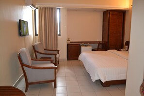 A hotel room with a bed, two chairs, a desk, and a wardrobe. - Planet Hotel (Douala)