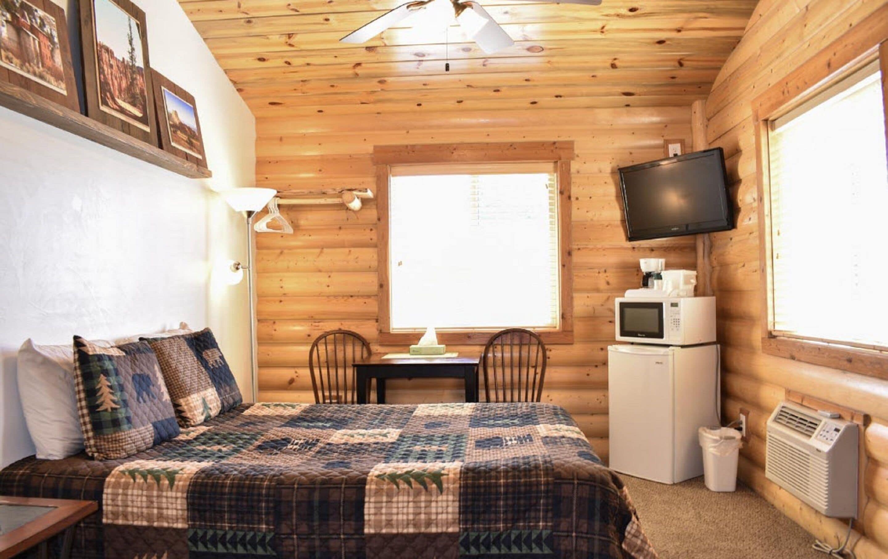 A cozy cabin room with a bed, a desk, a chair, a television, and a window.