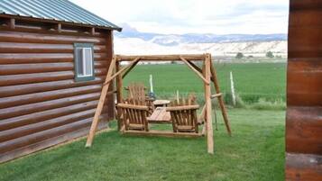 Situated in a serene natural setting, this cabin features a cozy porch with a swing and outdoor seating.