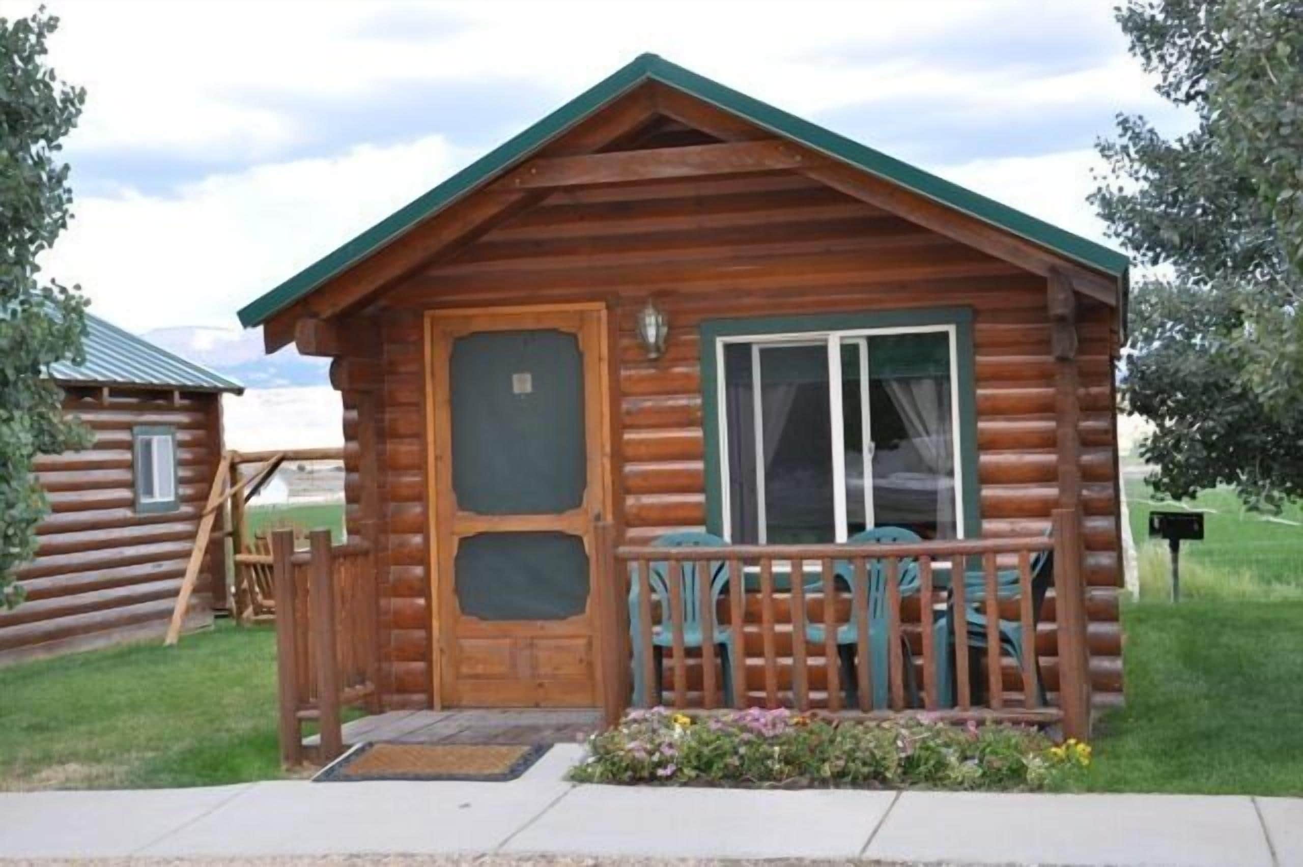 A log cabin with a front porch, a door, and a window.