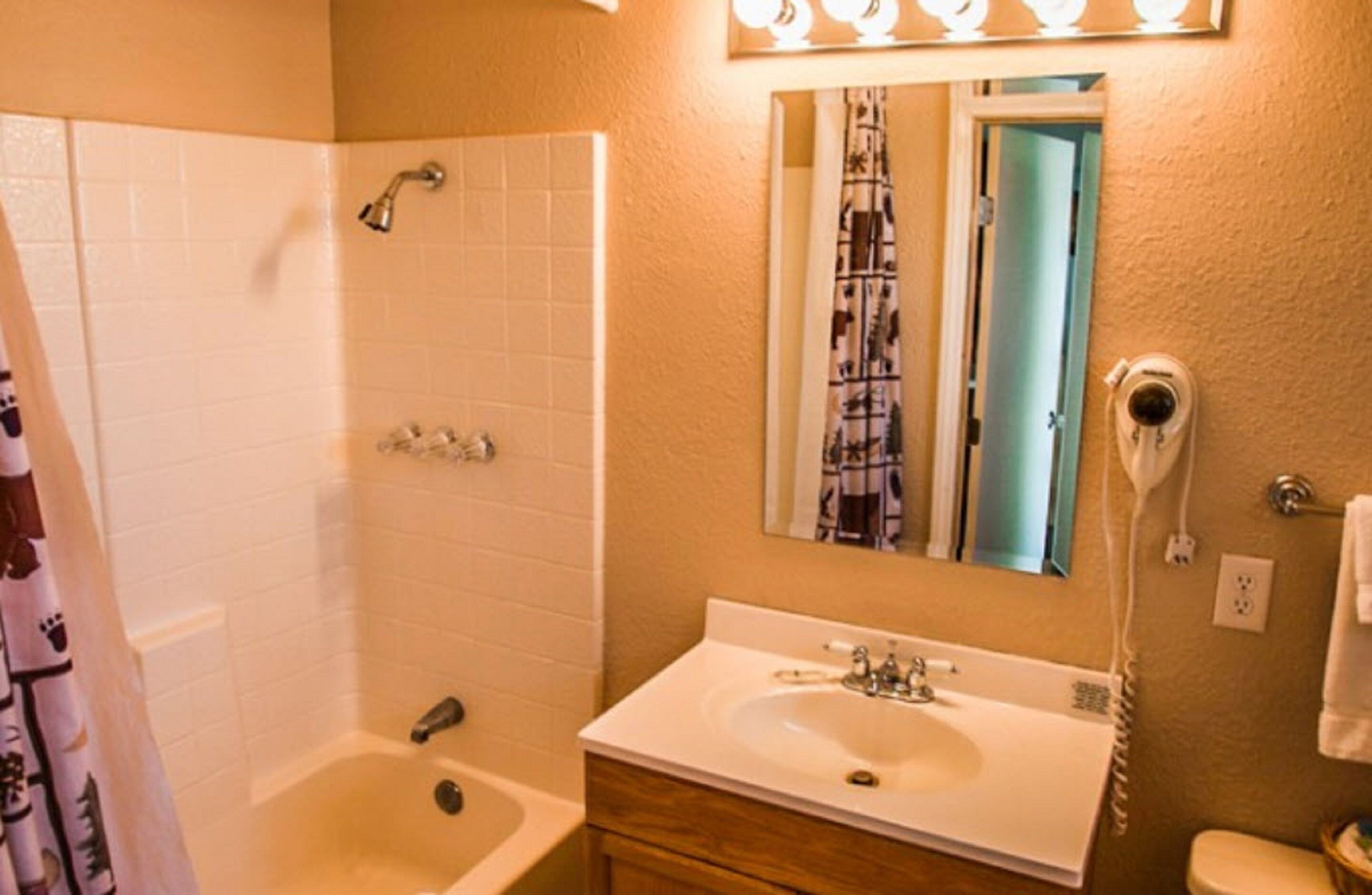 A bathroom with a white bathtub, a sink, a mirror, and a toilet.