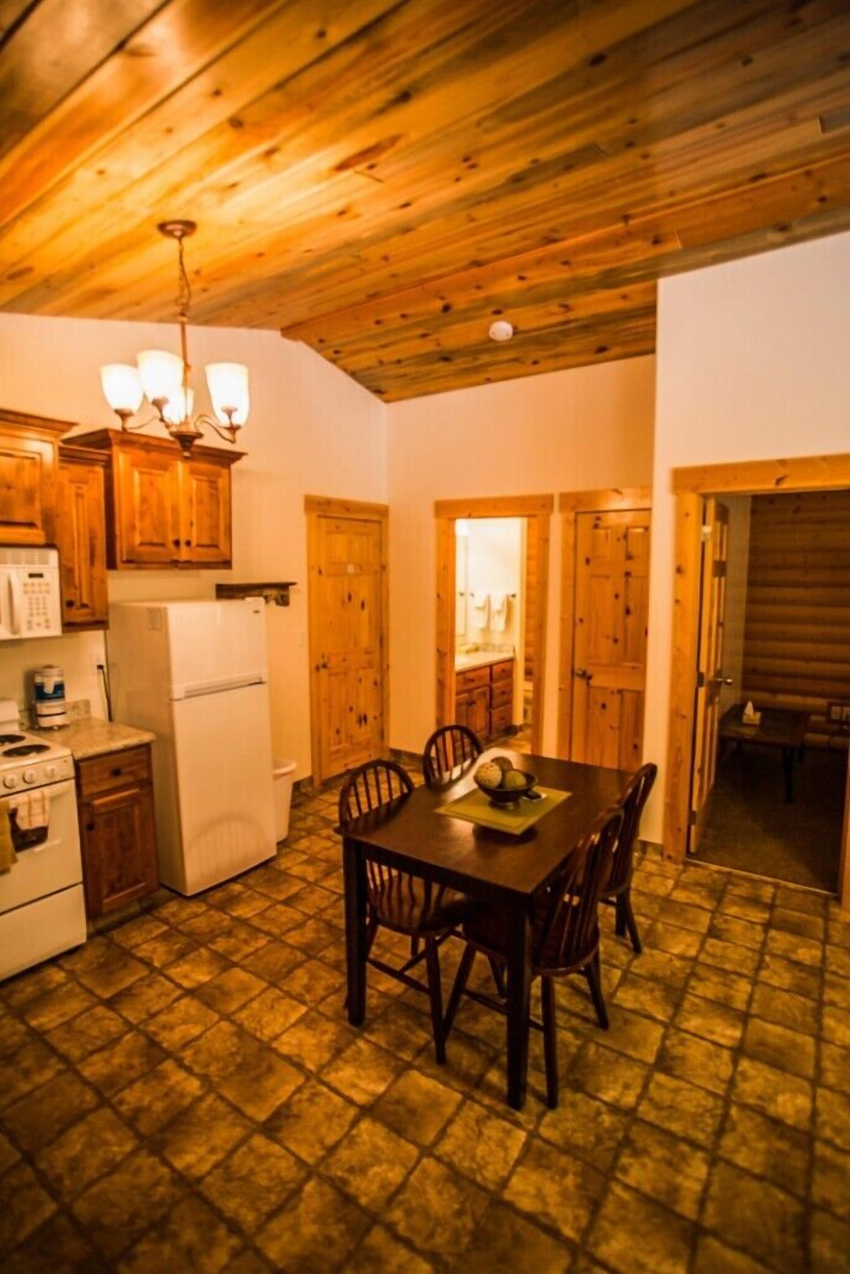 A kitchen with wooden cabinets, a dining table, and a tiled floor.