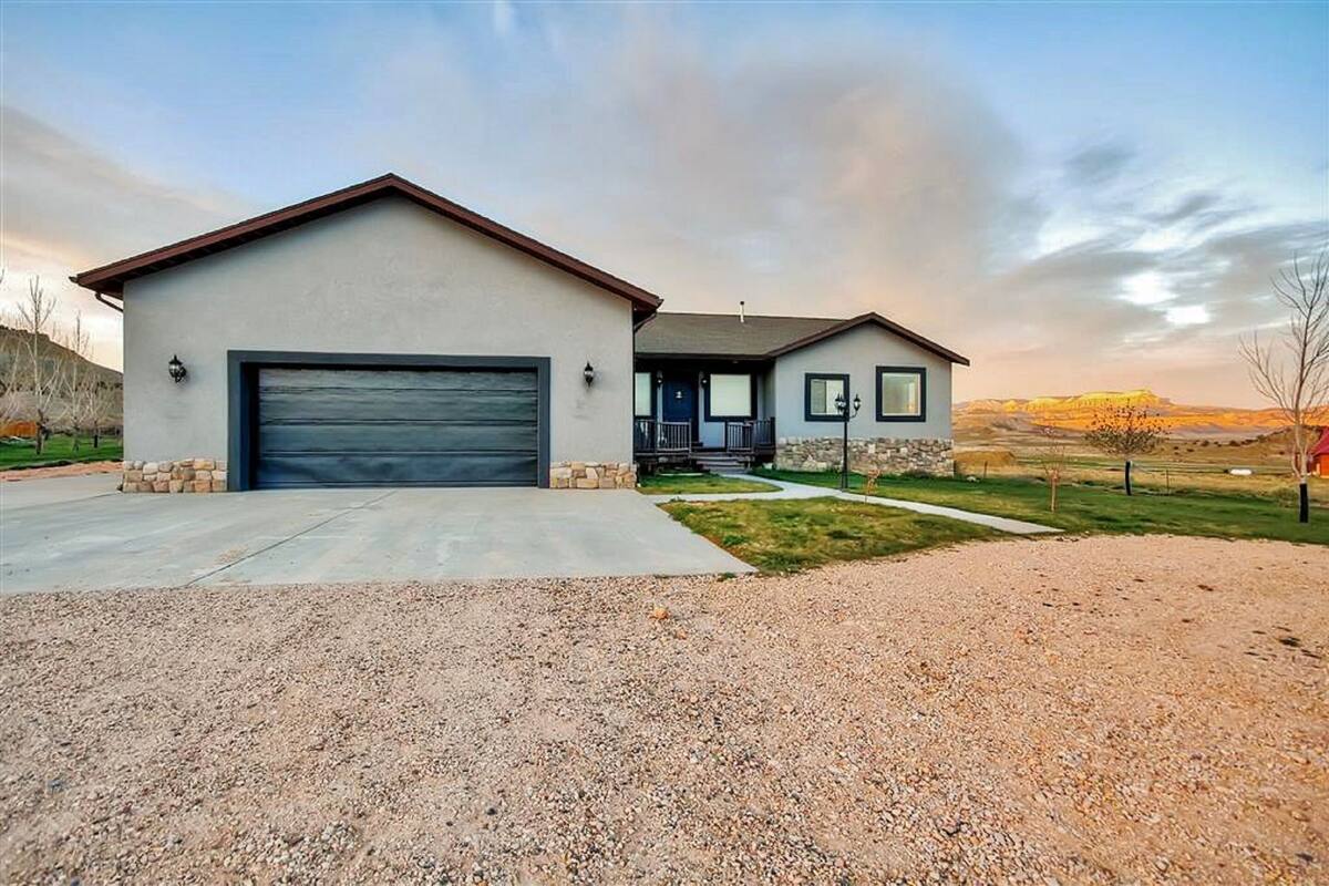 A modern two-story house with a garage, a stone foundation, and a well-maintained lawn.