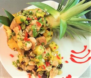 A plate of food with pineapple chunks, red peppers, and herbs. - La Jamaca (Lajas)