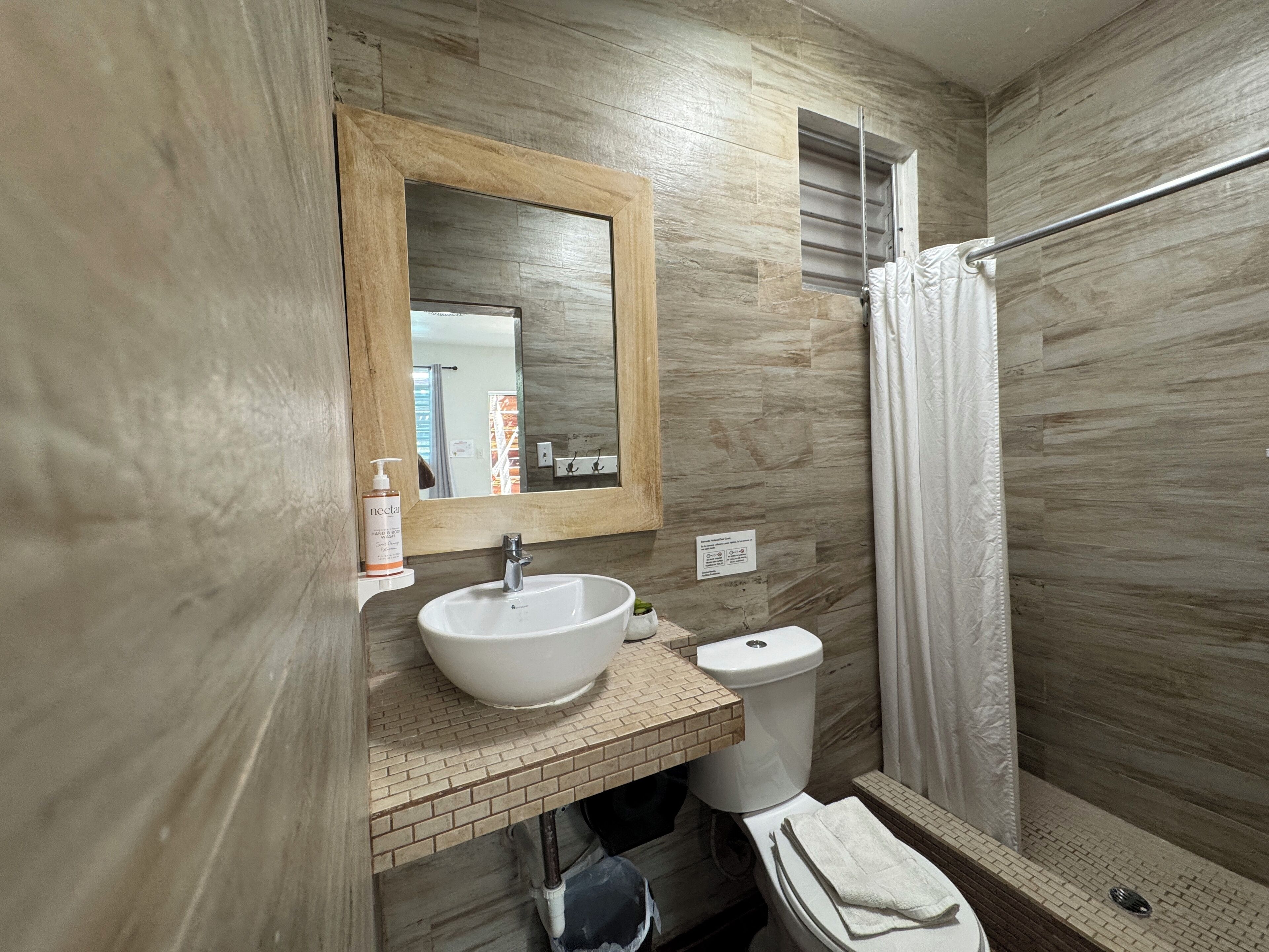 Une salle de bain avec un grand miroir, un lavabo, des toilettes et un espace douche.