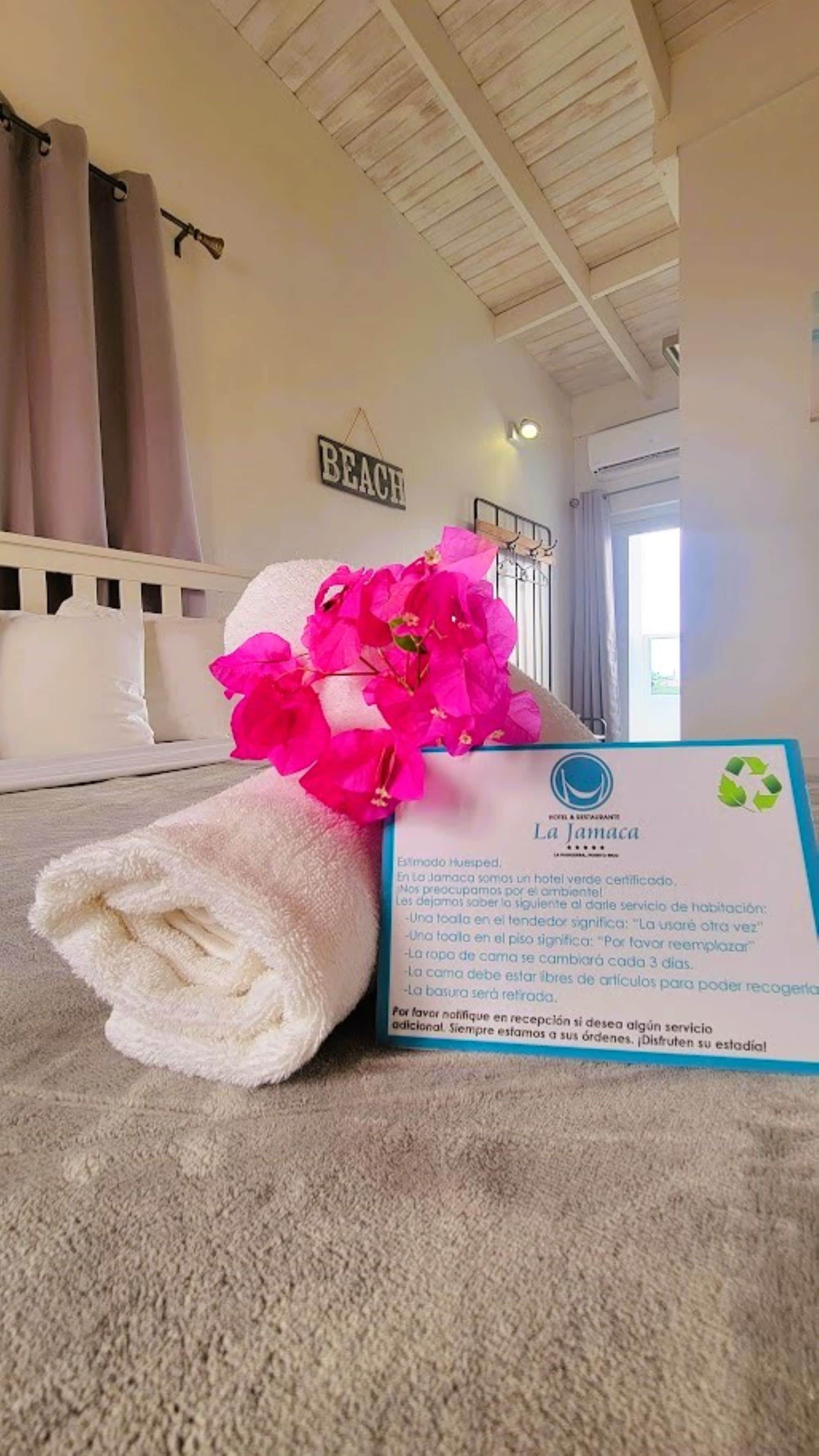 Una habitación de hotel con cama, toalla y un cartel con información del hotel.