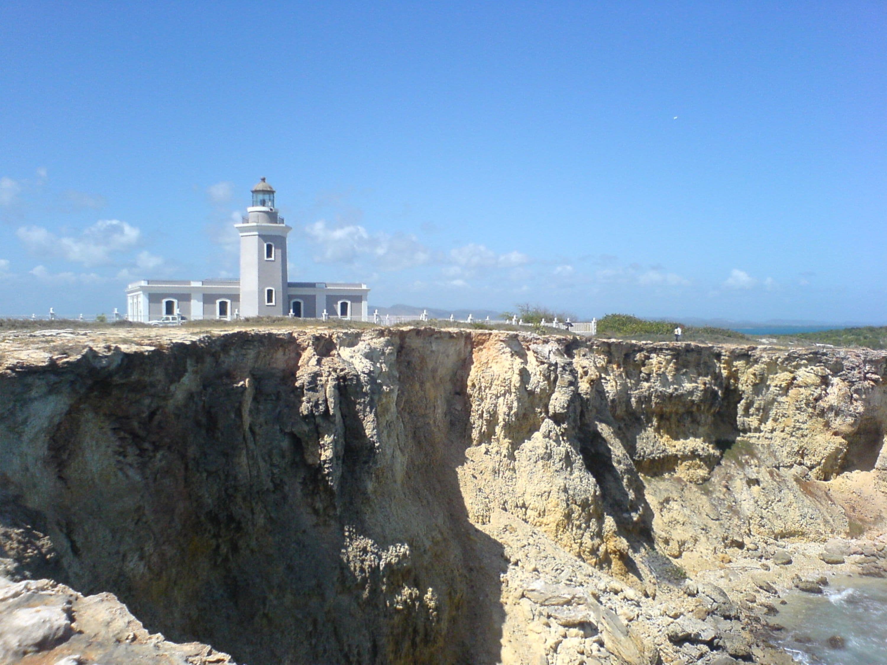A coastal building with a lighthouse, situated on a cliff overlooking the sea.