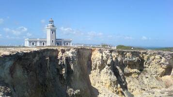 A coastal building with a lighthouse, situated on a cliff overlooking the sea.
