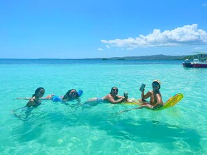 A group of people floating on a clear turquoise sea with a boat in the background. - La Jamaca (Lajas)
