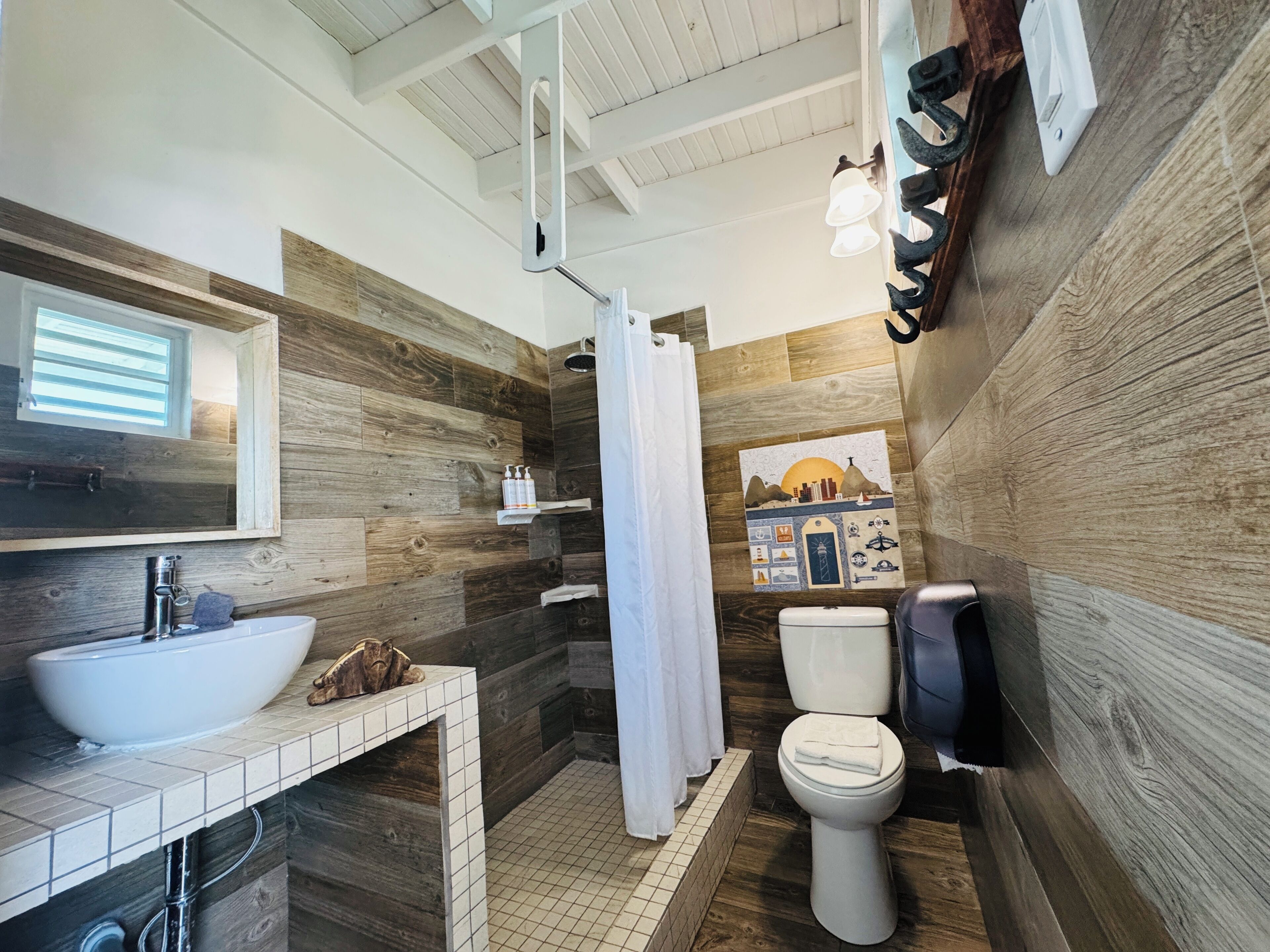A bathroom with a wooden wall design, a white sink, a shower curtain, and a toilet.
