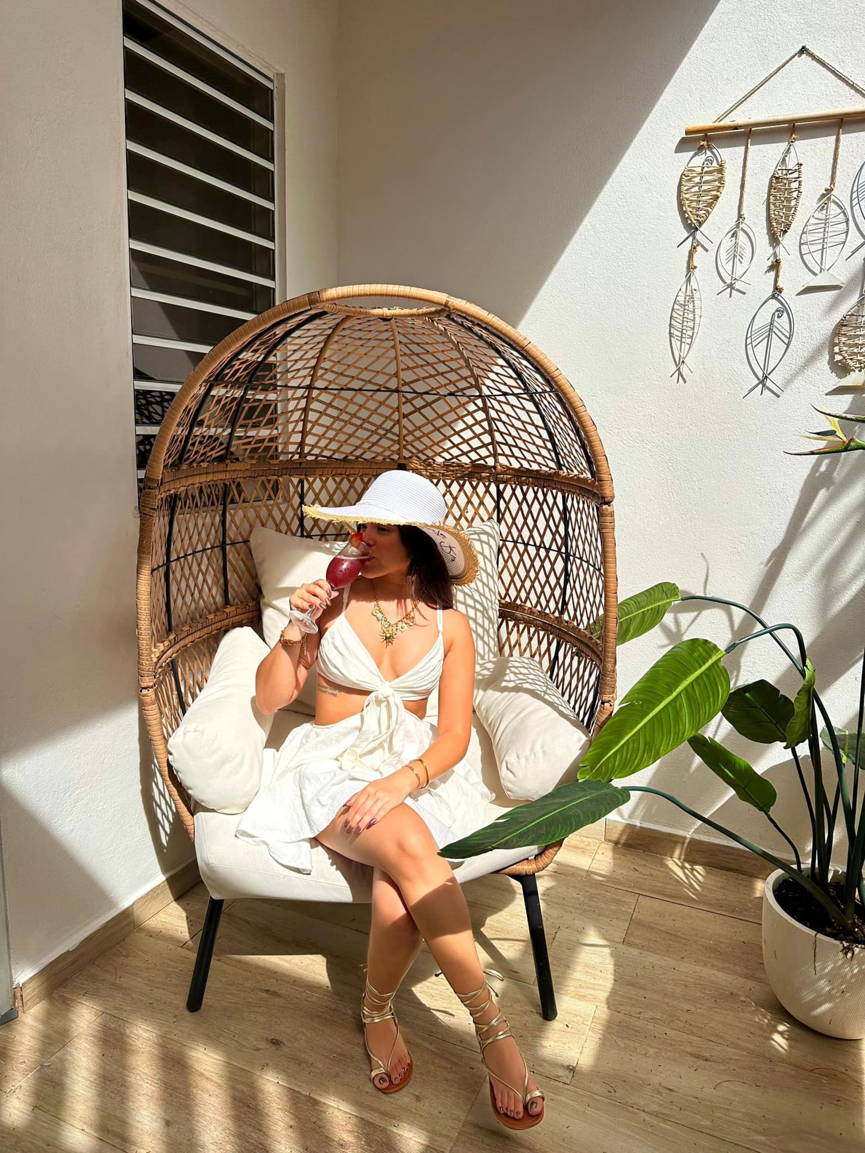 A wicker chair with a cushion, a potted plant, and a wall decoration.