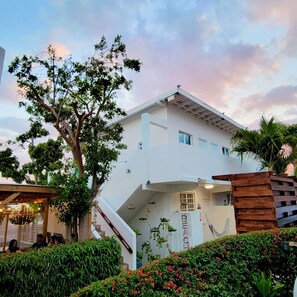 A modern two-story house with a white exterior, a covered porch, and a staircase leading to the entrance.