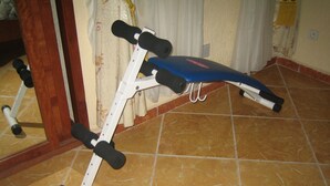 Een fitnessruimte thuis met een bankdrukapparaat en gewichten.