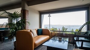Una sala de estar moderna con un sofá de cuero, una mesa de centro de vidrio y un amplio ventanal con vista al mar.