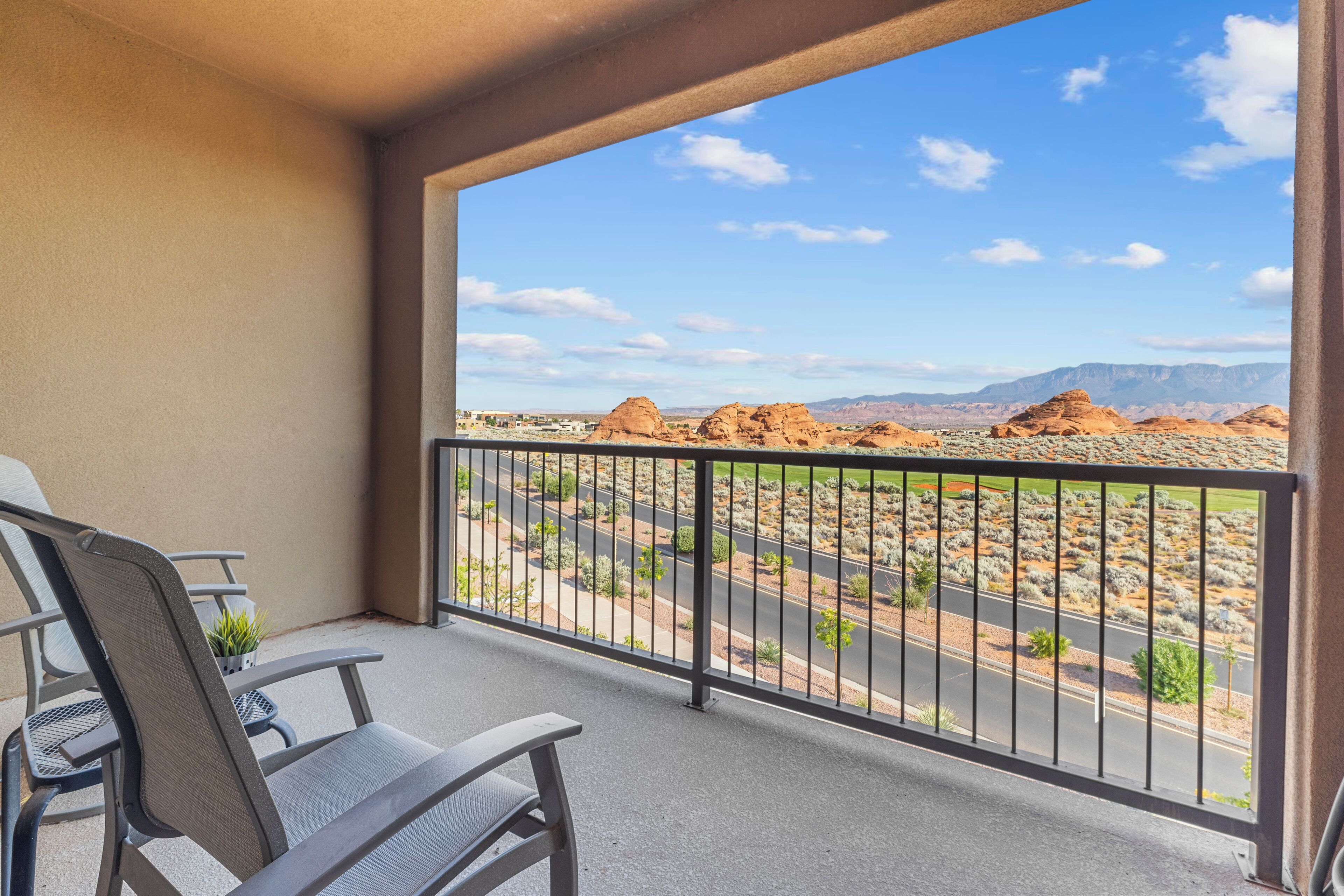 A balcony with a view of a desert landscape, including mountains and a road.