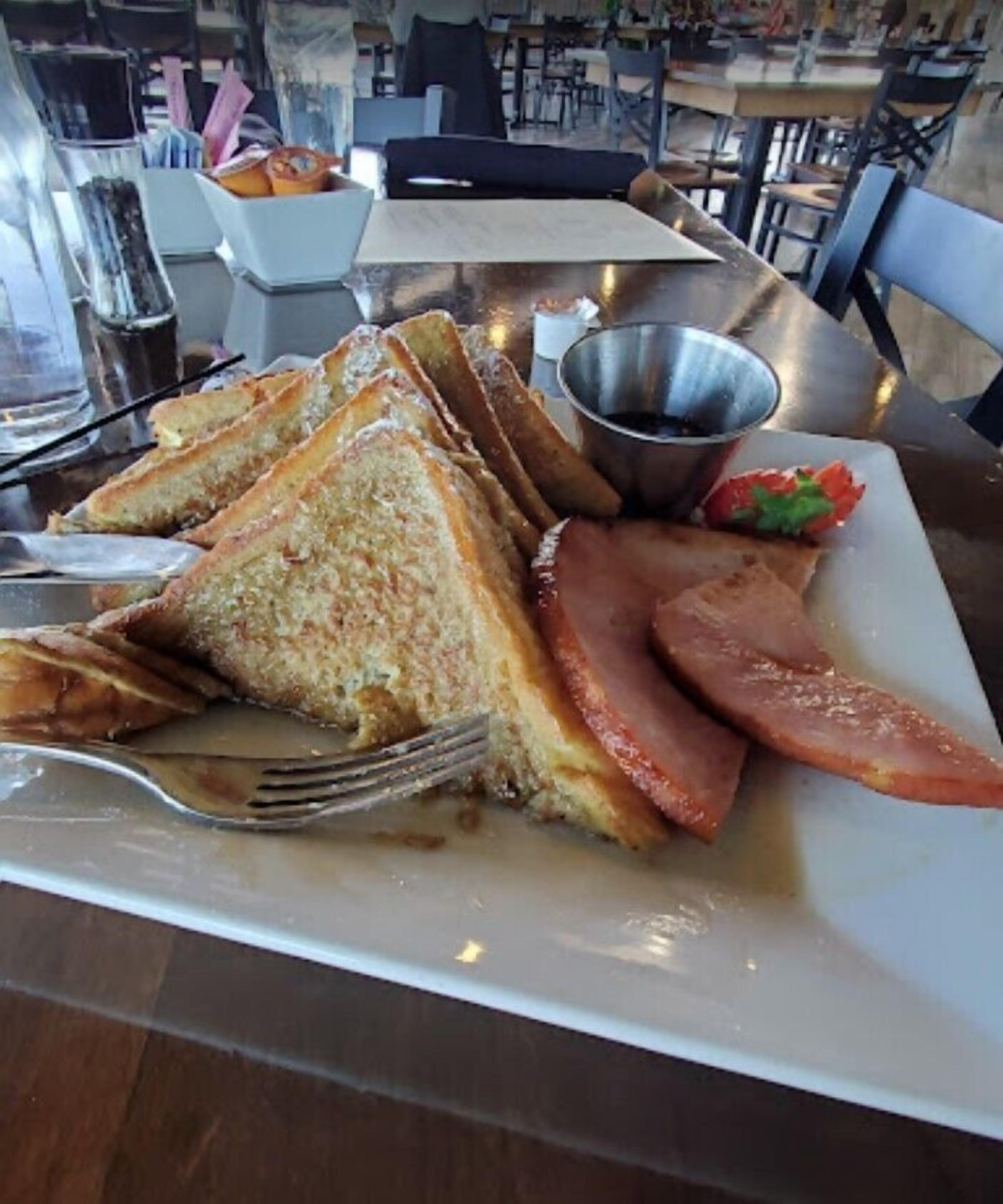 A plate with toasted bread, ham, and a small salad.