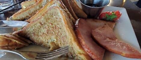 A plate with toasted bread, ham, and a small salad.