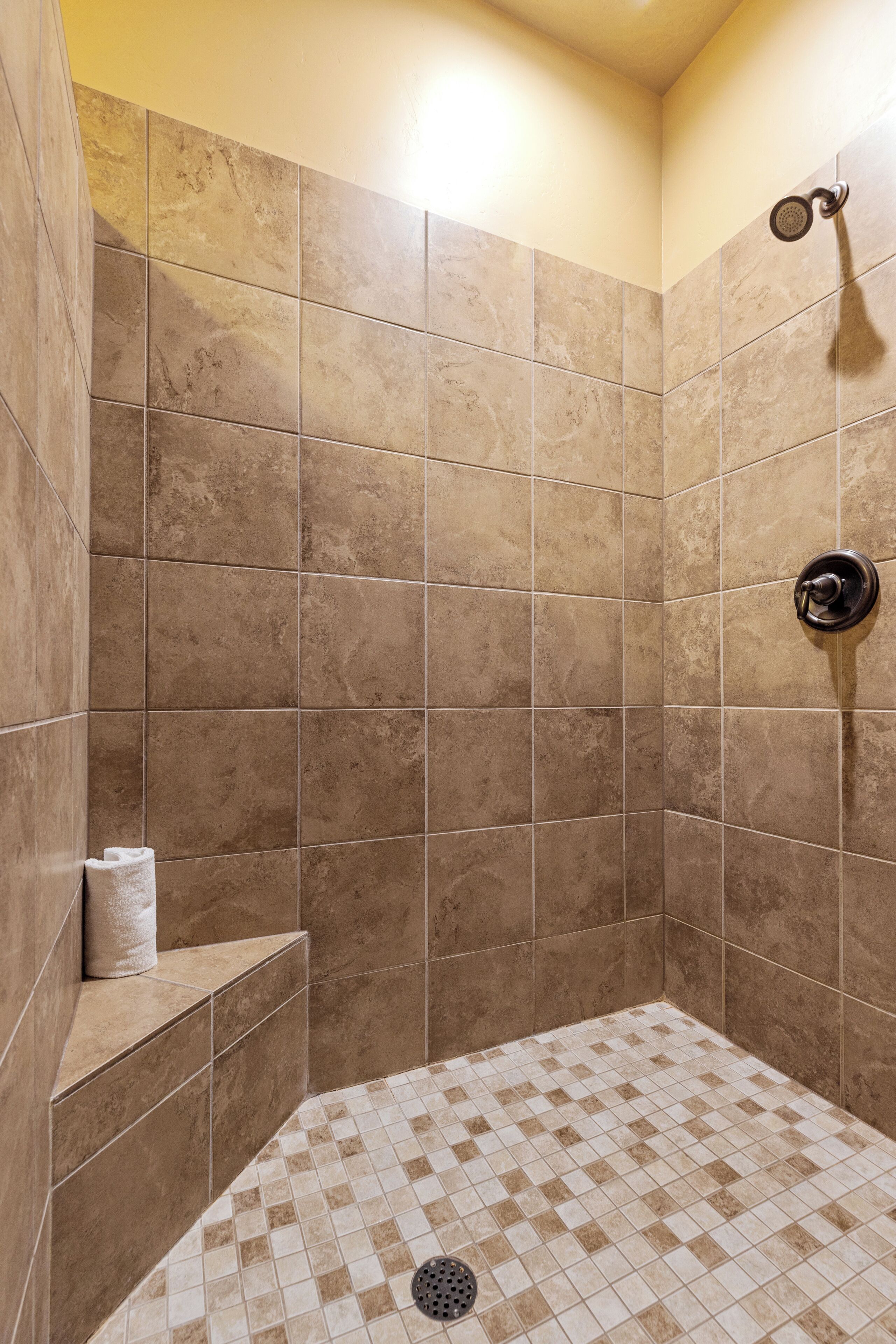 A shower area with beige tiles, a showerhead, and a towel rack.