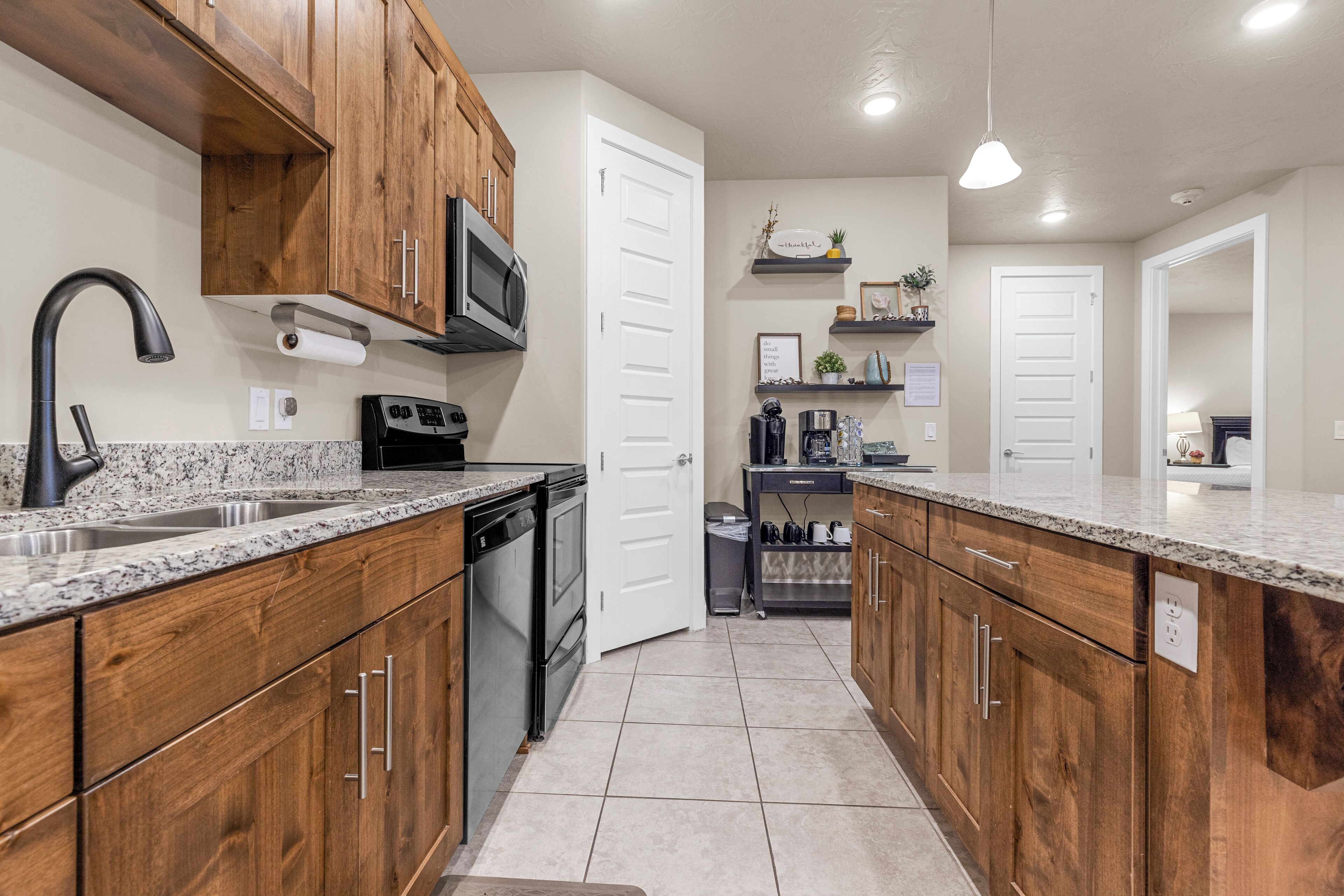 A kitchen with wooden cabinets, granite countertops, a stainless steel sink, a microwave, and a dishwasher.