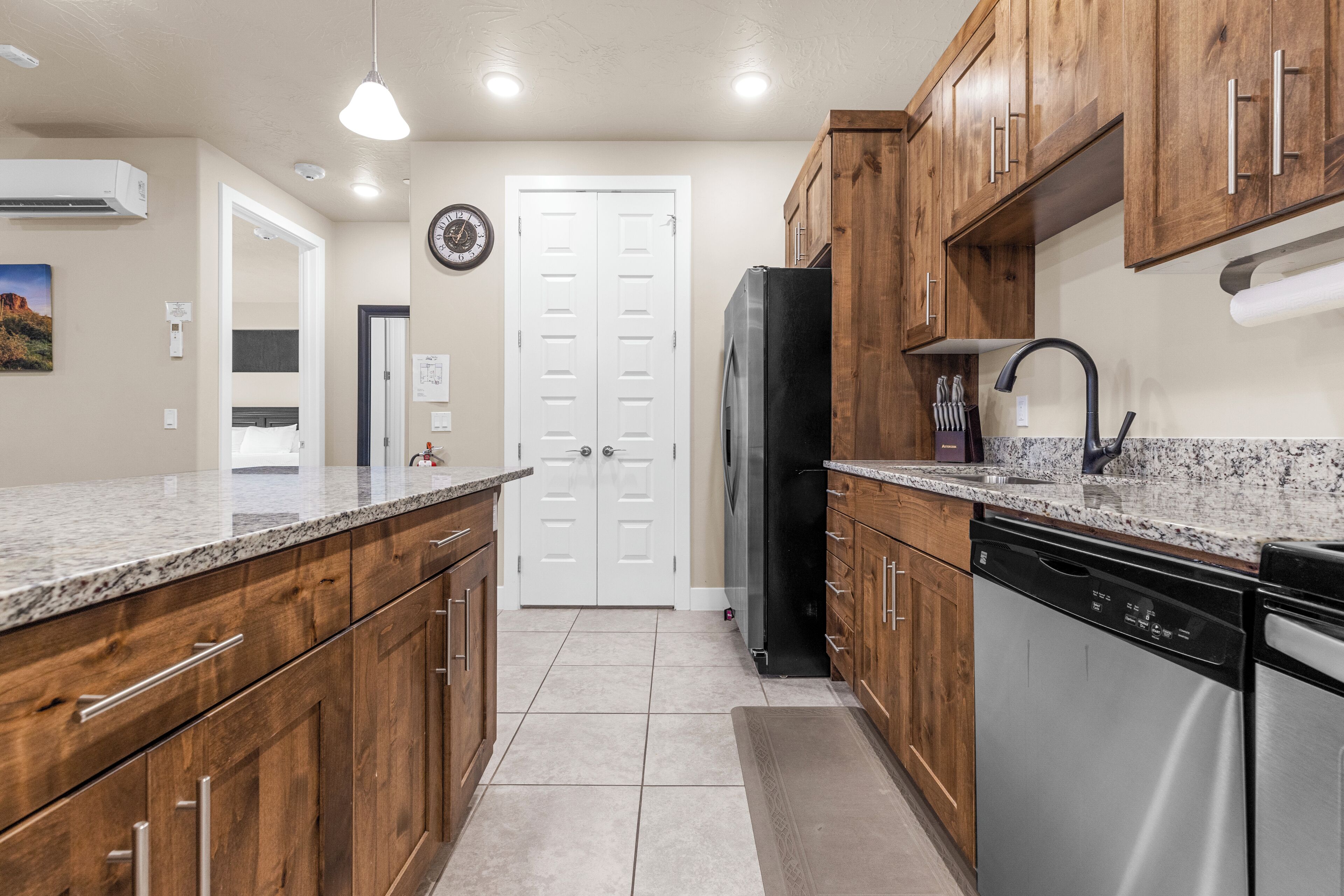 A kitchen with wooden cabinets, a stainless steel dishwasher, and a black refrigerator.