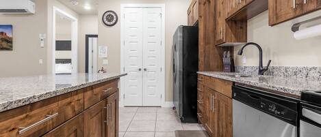 Una cocina con armarios de madera, lavavajillas de acero inoxidable y refrigerador negro.