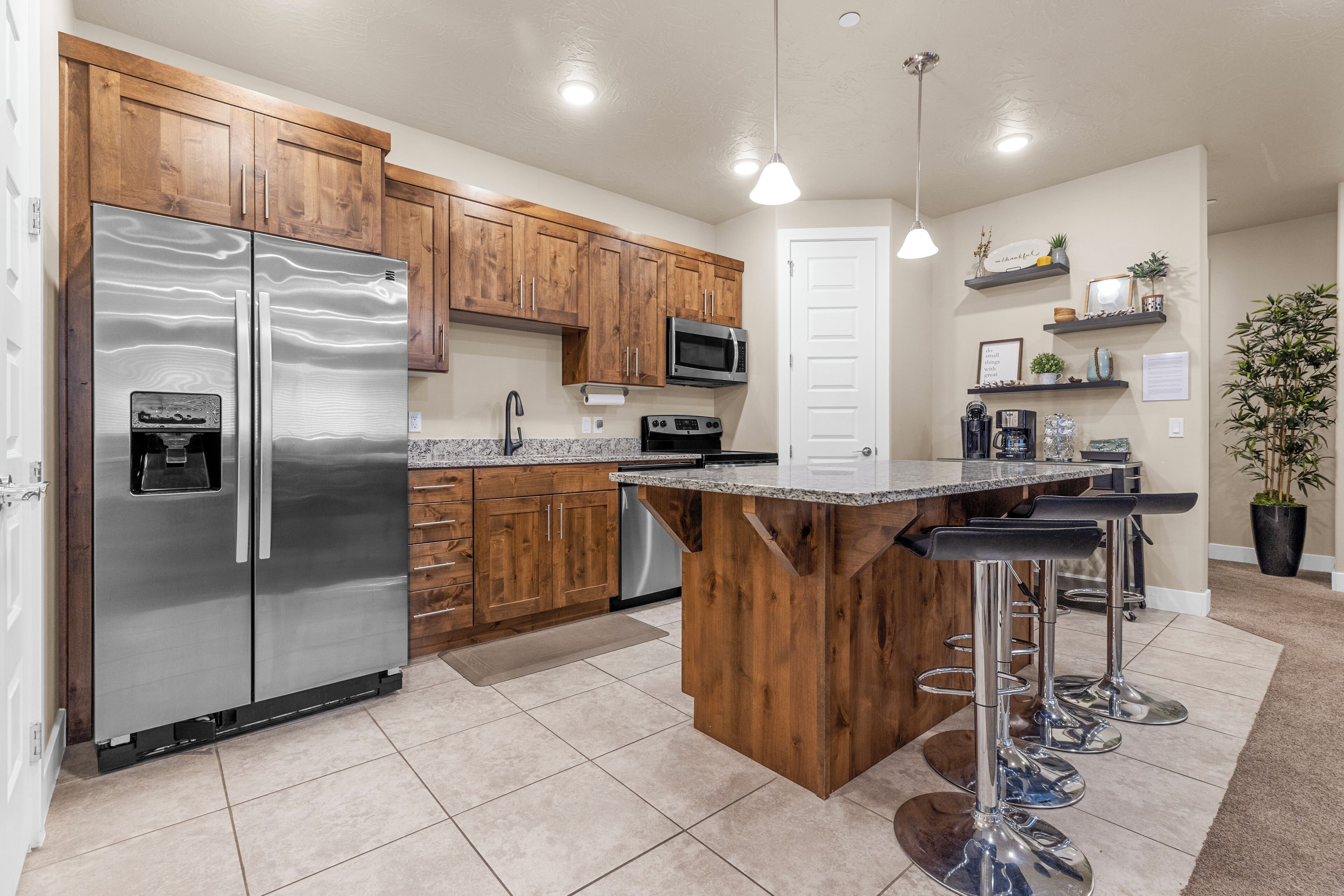 A modern kitchen with stainless steel appliances, wooden cabinets, and a central island with bar stools.