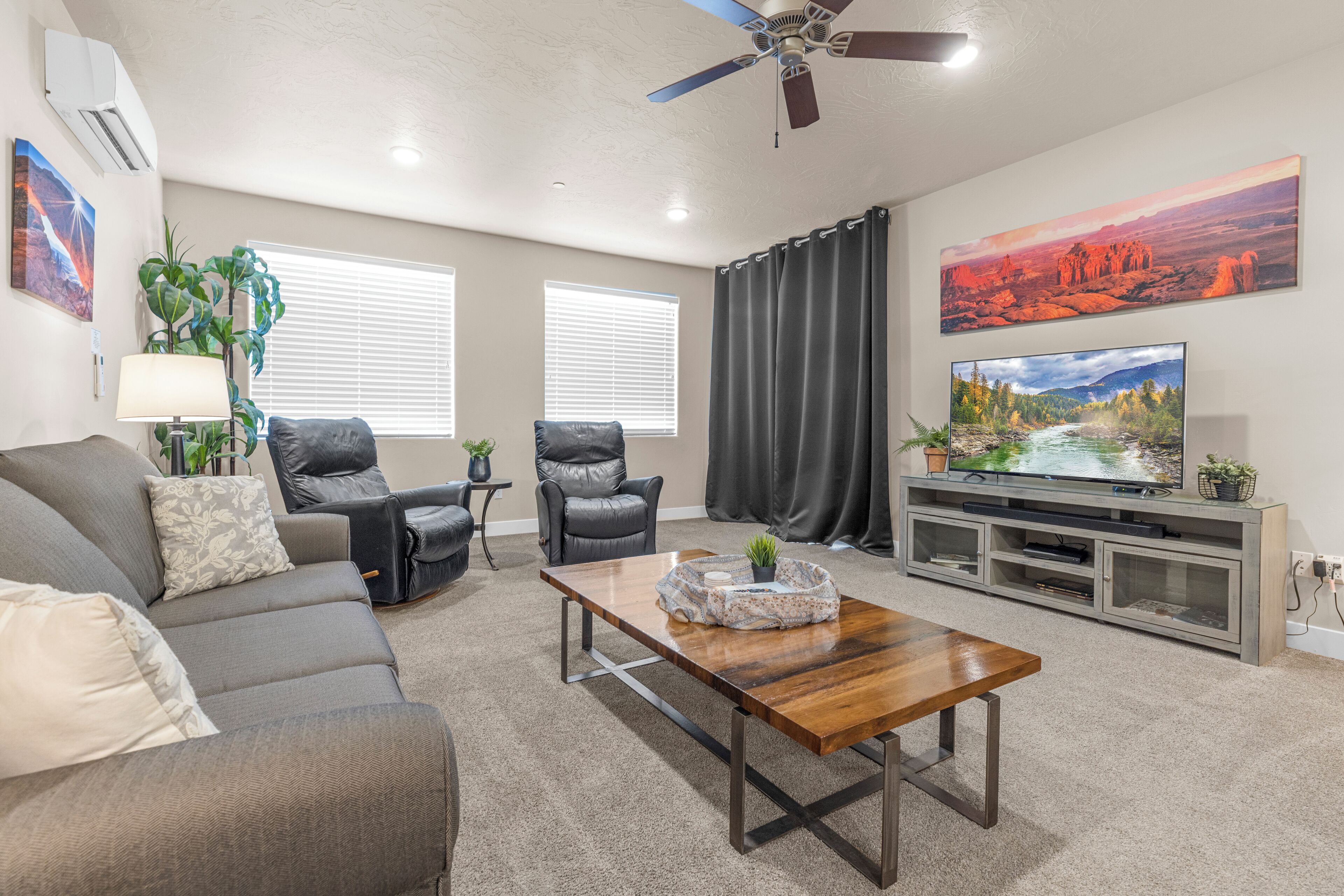 A living room with a sofa, two chairs, a coffee table, a TV, and a ceiling fan.