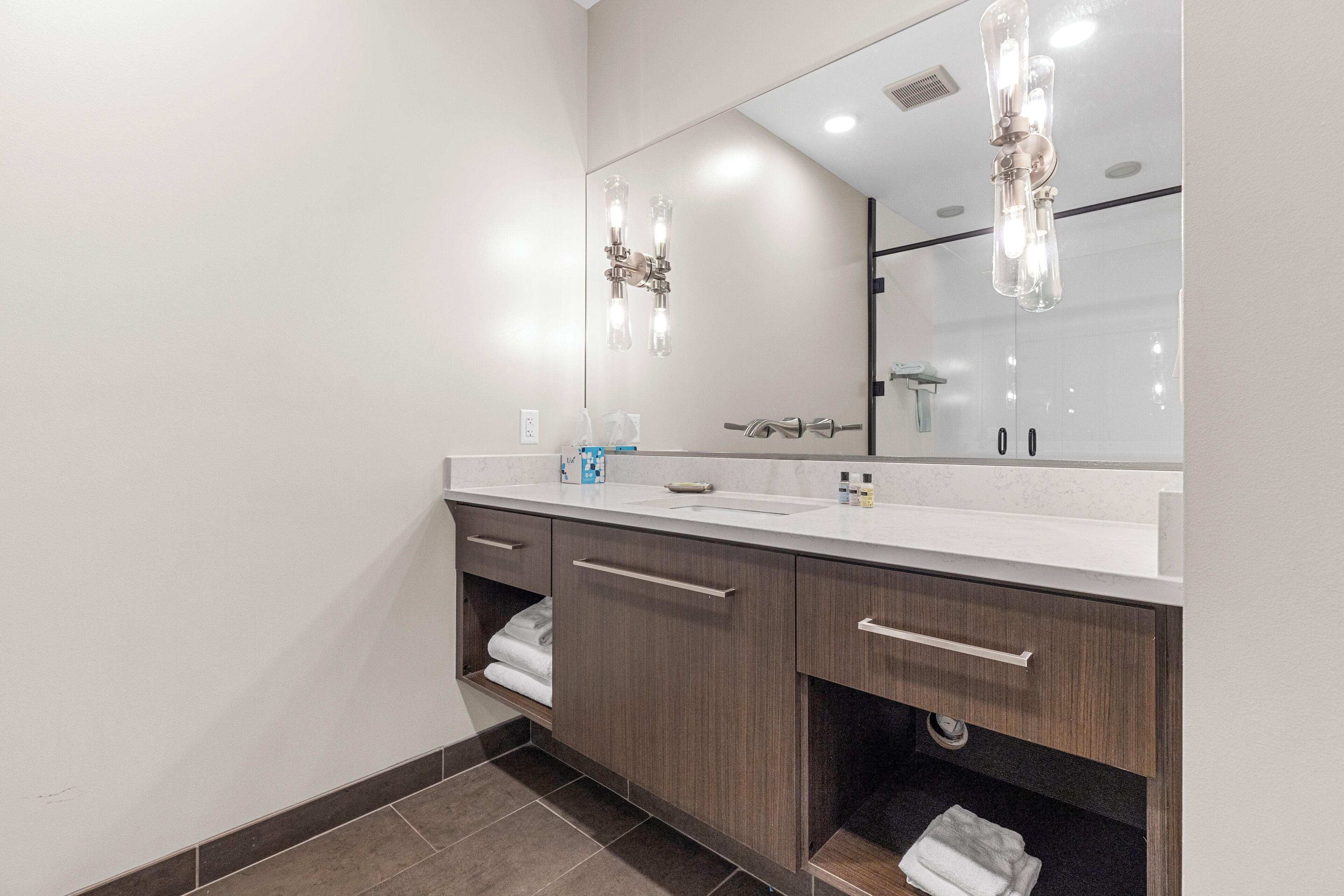 Un bagno moderno con uno specchio grande, due lavabi, mobili in legno e un porta asciugamani.